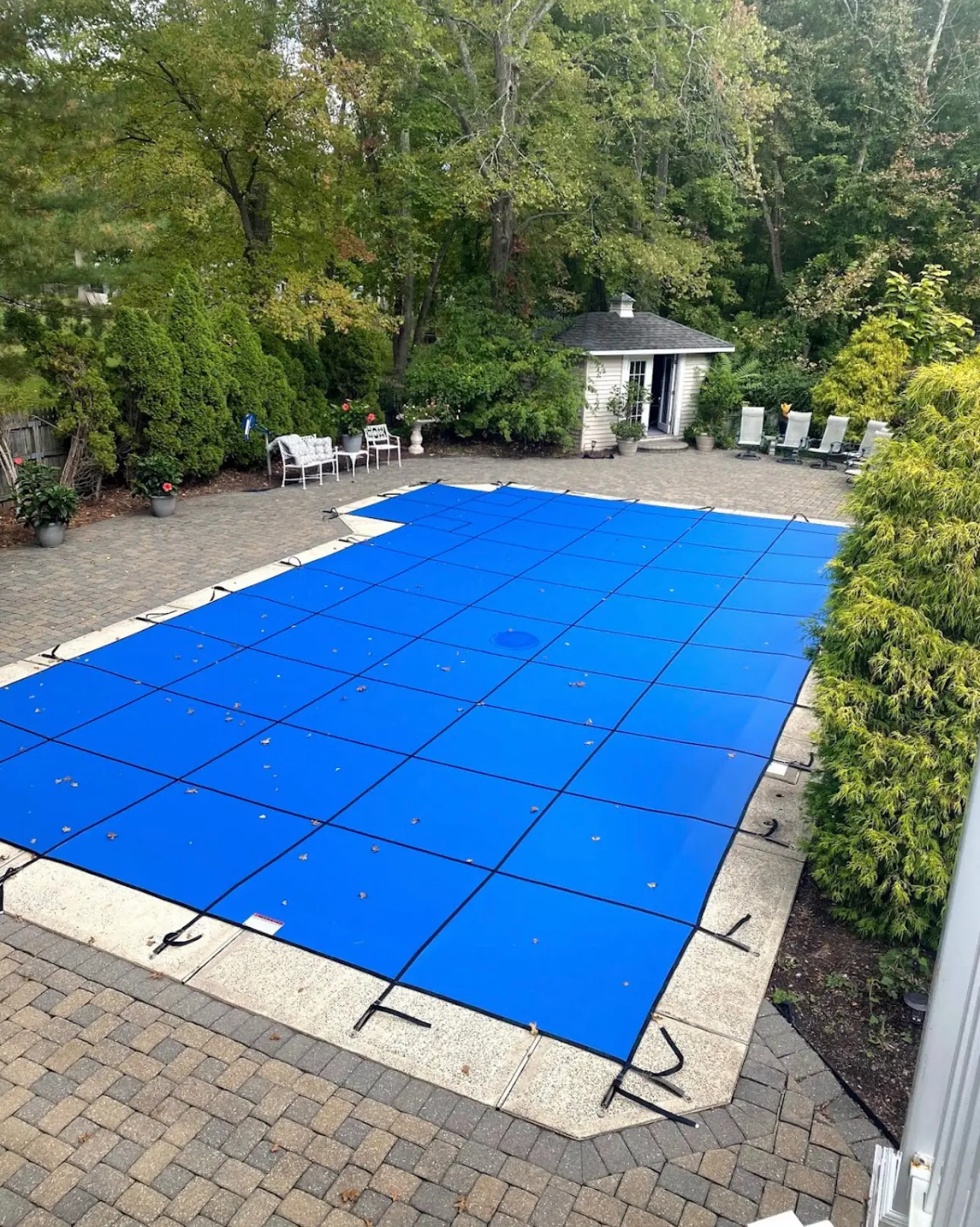 A pool cover is shown in the middle of a backyard.