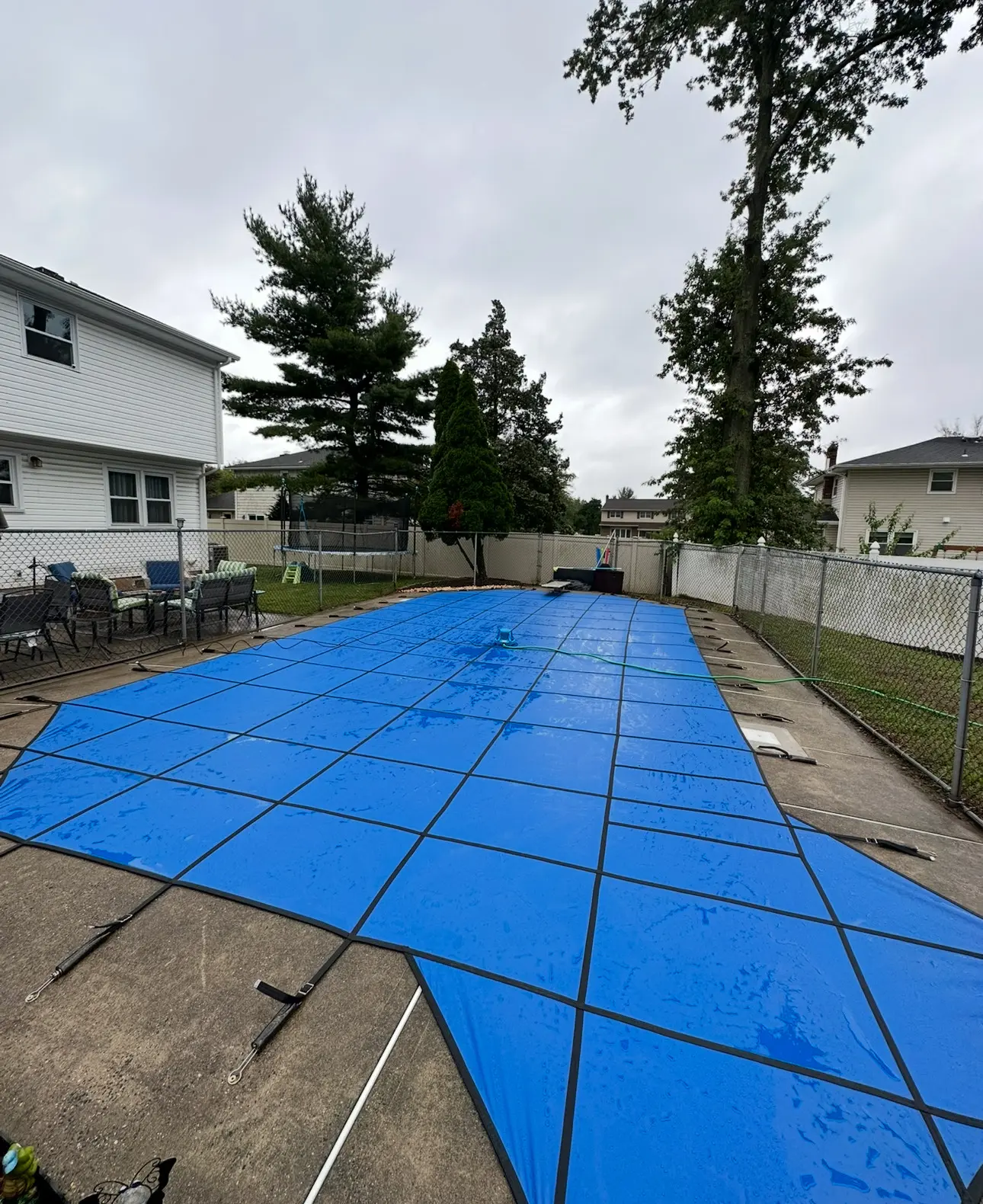 A pool cover is being installed in the backyard.