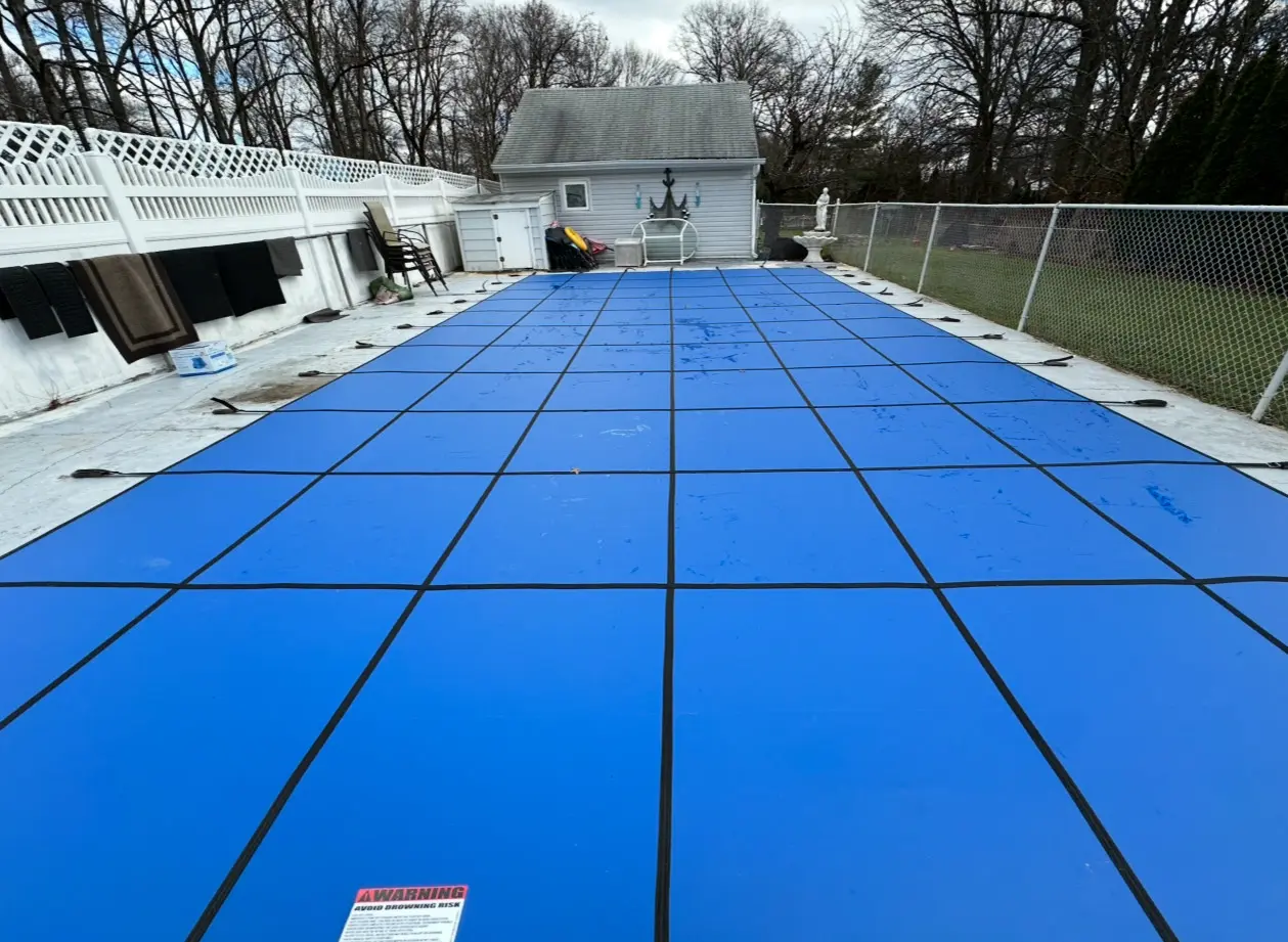 A pool cover is being installed in the backyard.