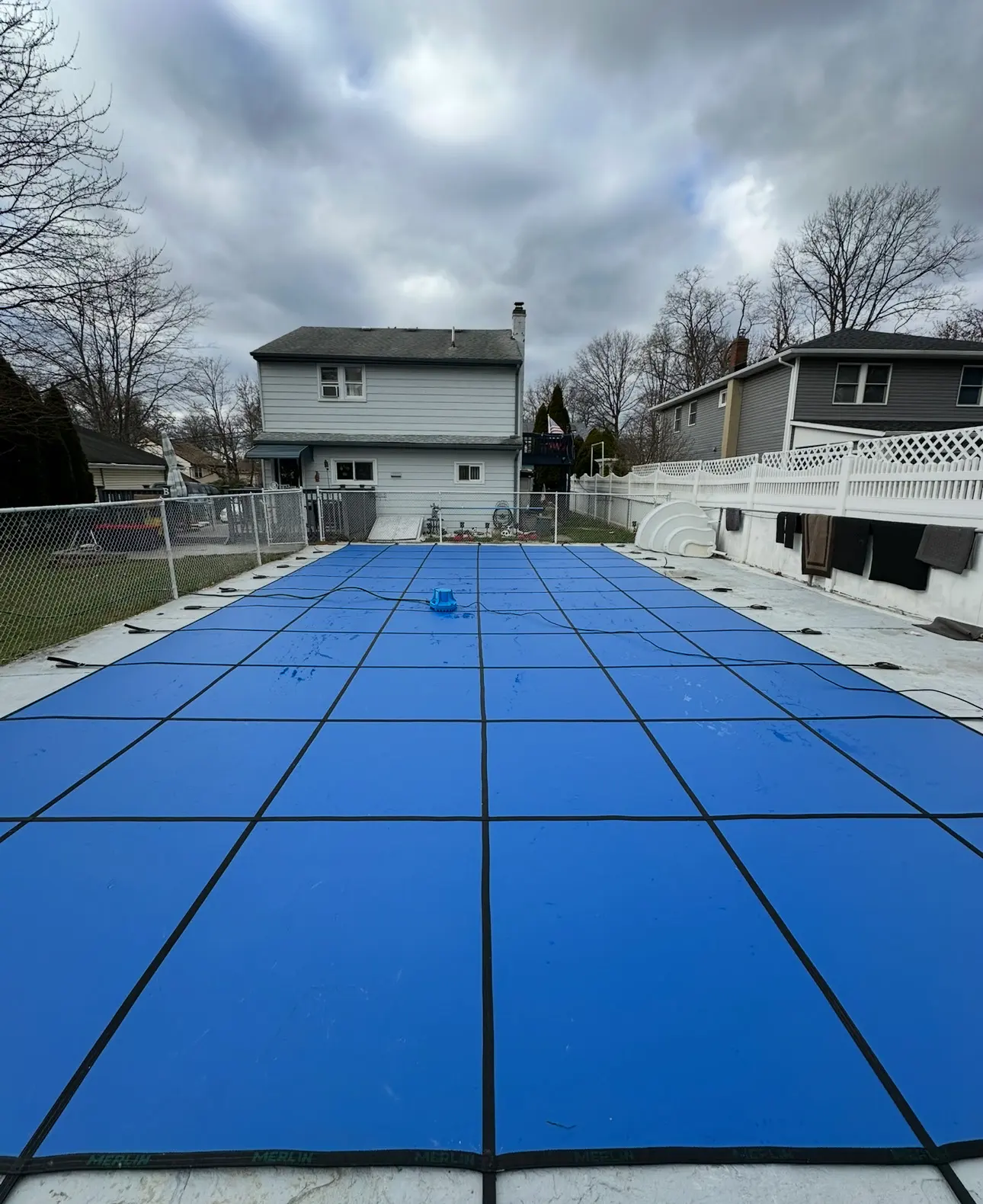 A pool cover is being installed in the backyard.
