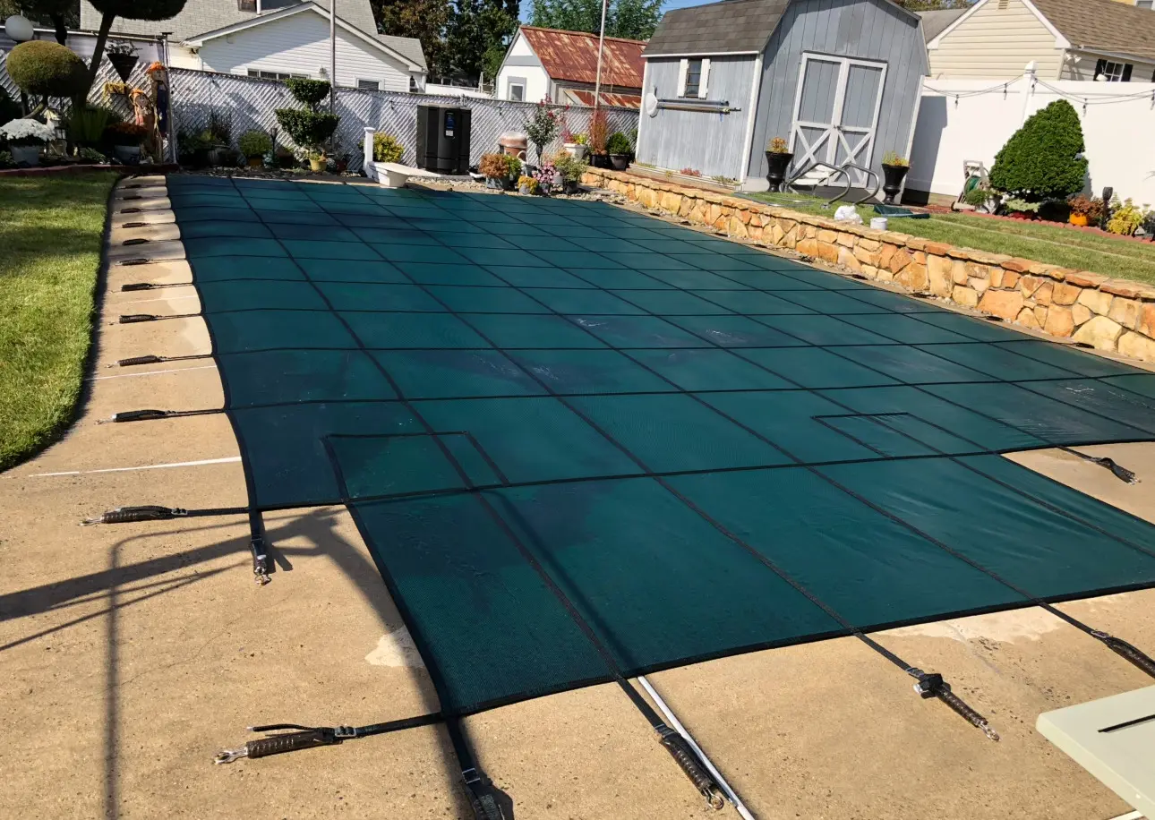 A pool cover is being installed in the backyard.