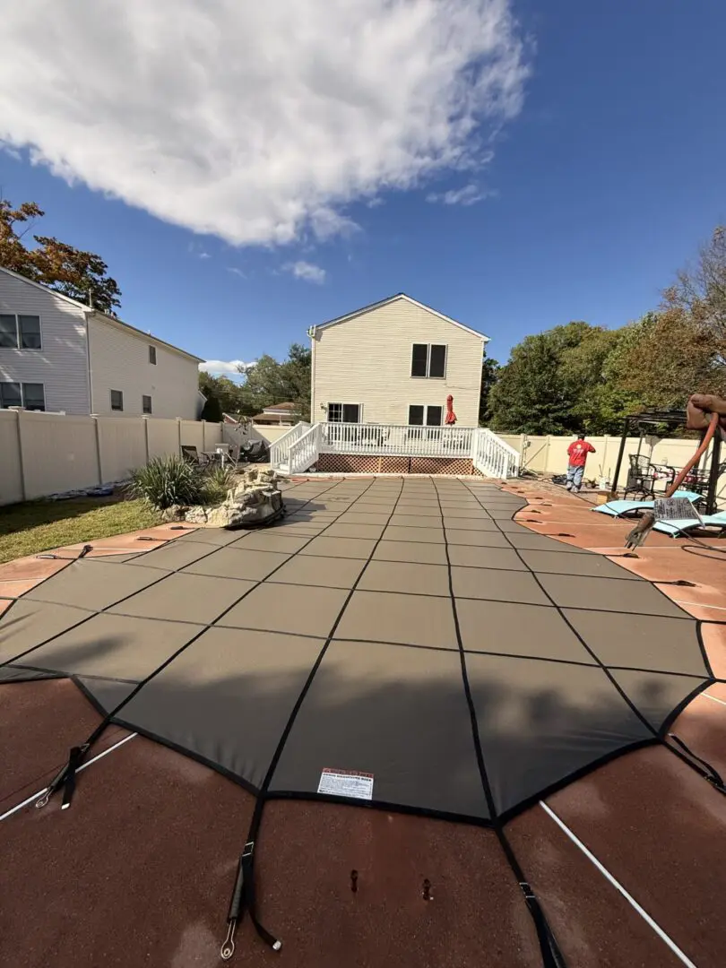 Pool cover spread across a backyard patio
