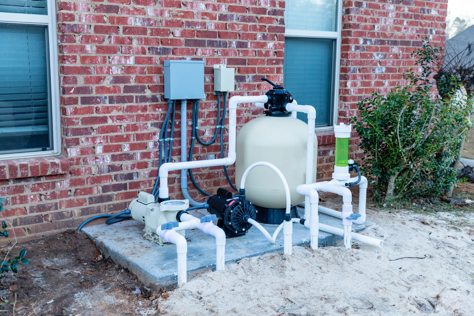 A pool pump and sand filter system in the backyard.